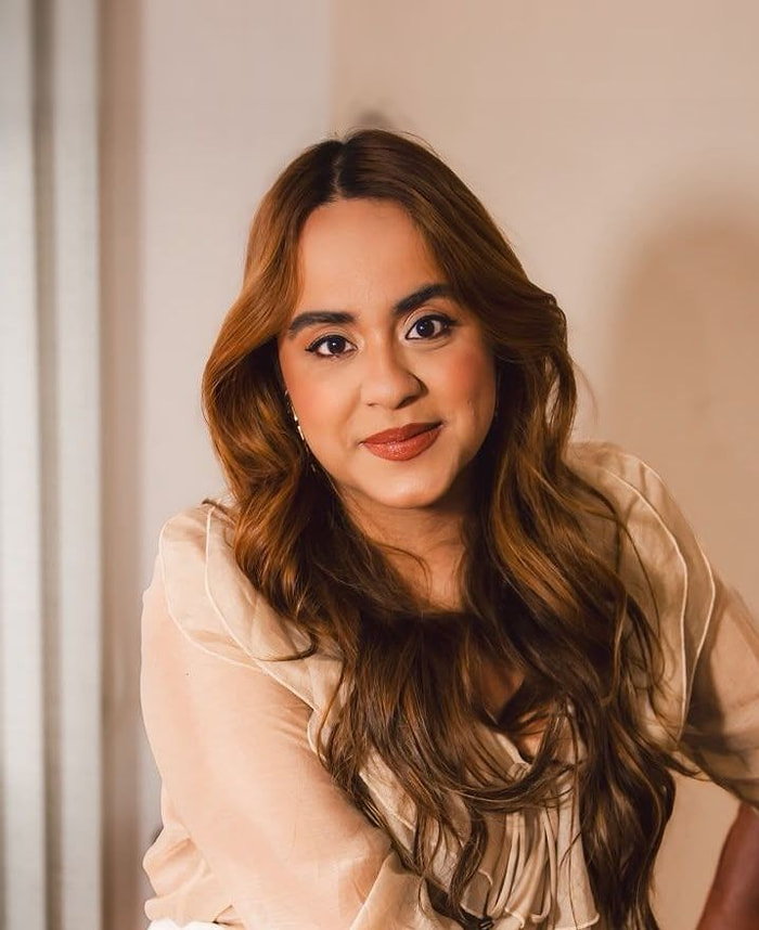 Juliana Almeida, psicóloga, sorrindo sentada no consultório